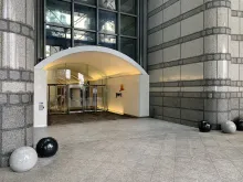 The entrance to PwC offices at 1 Embankment Place in London, with the PwC logo on the wall beside the revolving doors.
