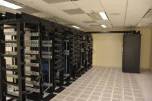 Rows of rack-mounted servers and network patch panels in a data center with a raised tile floor.