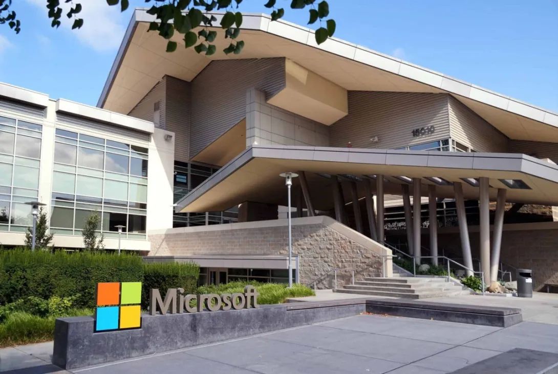 A Microsoft campus building in Redmond, Washington, with the Microsoft logo sign in the foreground on a sunny day.