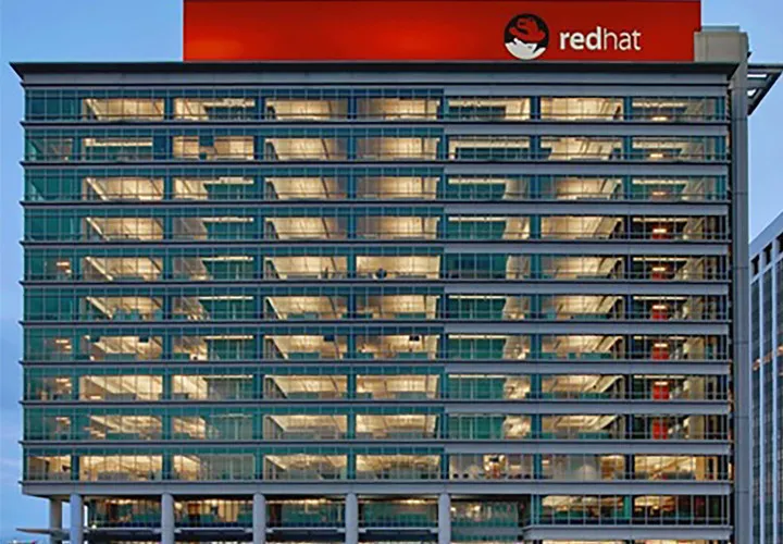 Red Hat Tower in Raleigh, North Carolina, its glass facade lit at dusk beneath the red Red Hat sign.